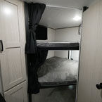 Partial of Pantry Door Shown, Double Over Double Bunks with Two Black Privacy Curtains and Grab Handle Next to Bathroom Door Shown Closed
 May Show Optional Features. Features and Options Subject to Change Without Notice.