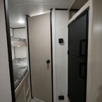 Two Bunks Next to Bathroom Door Shown Closed Next to Refrigerator. 

 May Show Optional Features. Features and Options Subject to Change Without Notice.