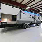 Door Side with Camp Kitchen and Pass through Storage Open, Optional Solid Steps Extended, Awning LED Lights On Shown in Blue.
 May Show Optional Features. Features and Options Subject to Change Without Notice.