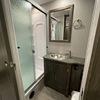 bathroom view of Lavatory Sink, mirror, cabinets and One Piece ABS Shower Surround with glass door May Show Optional Features. Features and Options Subject to Change Without Notice.