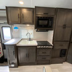 Kitchen with Cabinets and Microwave Overhead of Double Bowl Sink, Stove Top. Drawers and Cabinet Doors Below, Next to Double Door Pantry. May Show Optional Features. Features and Options Subject to Change Without Notice.