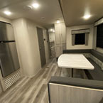 Stainless Steel Refrigerator Across From U-Shaped Dinette, Bathroom Door Shown Closed, Partial of Bunk Room Shown.
 May Show Optional Features. Features and Options Subject to Change Without Notice.