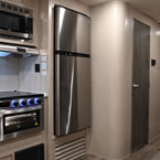 Stainless Steel Microwave Mounted Above Stainless Steel Oven/Stove Top, Next to Stainless Steel Refrigerator. Bathroom Door Shown Closed, Bunk Room Partially Shown.
 May Show Optional Features. Features and Options Subject to Change Without Notice.
