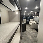 View from bunks looking towards front of coach with partial view of sofa and kitchen counter and sink
 May Show Optional Features. Features and Options Subject to Change Without Notice.