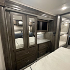 Bedroom view of cabinets with mirrors and drawers for storage and bedroom TV. Partial view of bunks in hallway
 May Show Optional Features. Features and Options Subject to Change Without Notice.